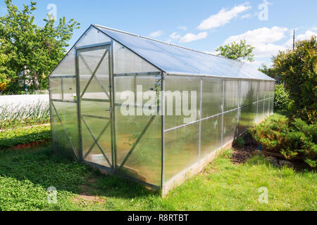 Serre en polycarbonate dans le jardin. Toit triangulaire. Banque D'Images