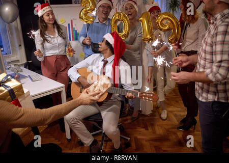 Groupe d'affaires à Santa hat à Noël parti au pouvoir célébrer avec la chanson Banque D'Images