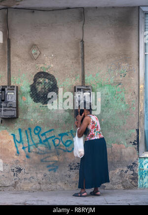 La femme cubaine sur un téléphone public à La Havane, Cuba. Une image emblématique de Che Guevara apparaît au-dessus d'elle - comme si une bulle. Banque D'Images