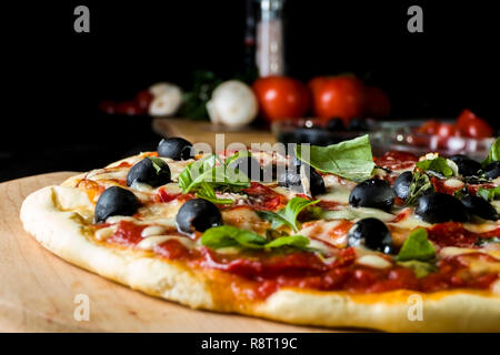 Pepperoni pizza cuite au salami, olives noires, basilic et fromage mozzarella. Banque D'Images