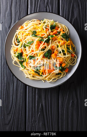 L'alph-spaghetti à la courge, épinards et fromage cheddar, close-up sur une plaque sur la table. Haut Vertical Vue de dessus Banque D'Images