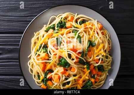 Repas spaghetti biologique avec le potiron, les épinards et le fromage cheddar gros plan sur une assiette sur la table. haut horizontale Vue de dessus Banque D'Images