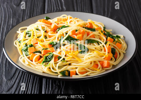 Recette spaghetti végétarien simple avec citrouille, épinards et fromage libre sur une plaque sur la table horizontale. Banque D'Images