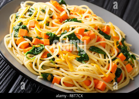 Une délicieuse cuisine italienne spaghetti avec du potiron, les épinards et le fromage cheddar close-up sur une plaque sur la table horizontale. Banque D'Images