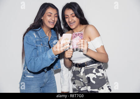 Teenage Twin Sisters en utilisant des téléphones intelligents Banque D'Images