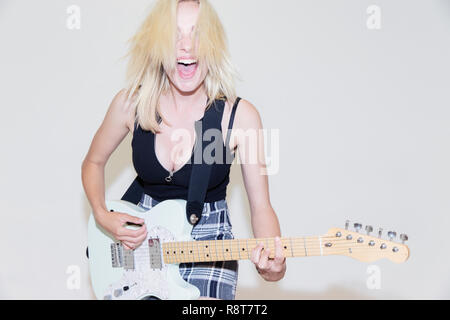 Exubérante Portrait young woman playing electric guitar Banque D'Images