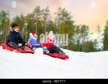 Les enfants glisser sur les traîneaux en hiver snow hill Banque D'Images