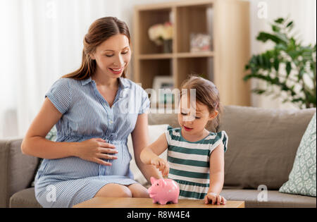 Mère et fille enceinte avec piggy bank Banque D'Images