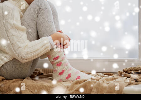 Fille assise sur la fenêtre de bas à la maison en hiver Banque D'Images