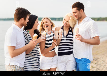 Happy friends eating ice cream on beach Banque D'Images