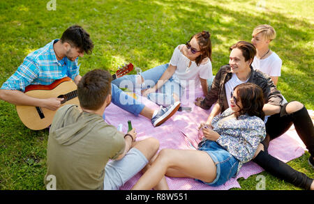 Les amis à jouer de la guitare à pique-nique au parc d'été Banque D'Images