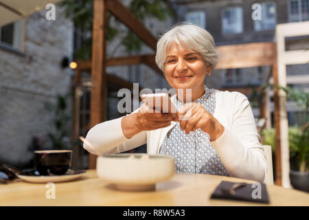 Senior woman photographing food at street cafe Banque D'Images