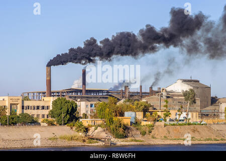 Changement climatique, réchauffement global : l'usine de sucre de l'Égypte sur le nil les éructations des volutes de fumée sale noir et épais et fumées provenant de ses cheminées Banque D'Images