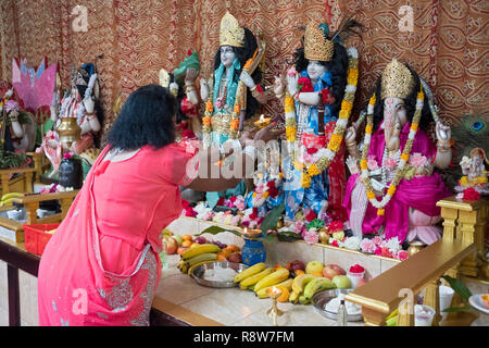 L'ARTI rituel. Une pieuse femme hindoue prie vagues feu devant des statues des divinités dans un temple dans le Queens, New York. Banque D'Images