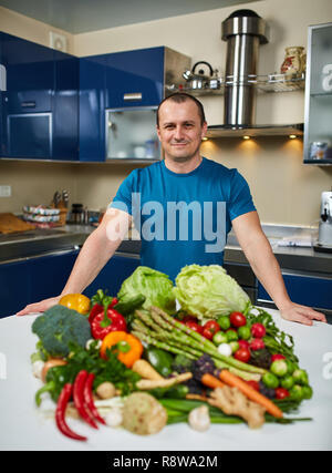 Homme avec une grande variété de légumes, prêts à être cuisinés Banque D'Images