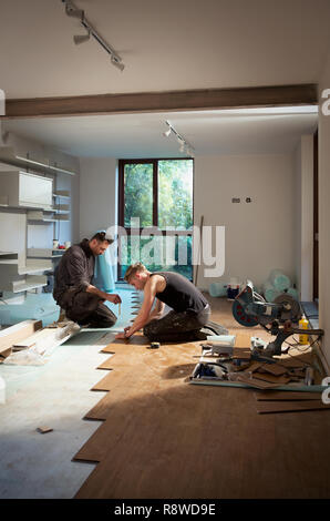 Les travailleurs de la construction pose de parquet dans chambre Banque D'Images