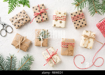 De nombreux cadeaux de Noël, les boulangers de l'épinette et de la ficelle sur le tableau blanc. Cadeaux enveloppés de papier kraft brun. Préparation OK Computer. Banque D'Images