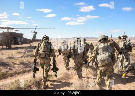 Des soldats américains avec le 11e Régiment de cavalerie blindée évacuer un soldat de jeu de rôle dans un UH-60 Black Hawk de la simulation d'une zone de combat après avoir sécurisé la zone d'atterrissage d'un hélicoptère pendant leur raid au cours d'assaut aérien National Training Centre 17-04 à Fort Irwin, en Californie, le 28 février 2017. Le but de cet exercice était de rétablir des communications stratégiques, qui sont décisives pour la mission du régiment de commandement pour les opérations militaires. Banque D'Images