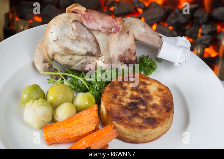 Ensemble Quail enrobé de bacon et rôti au four, servi avec des pommes de terre fondantes et légumes. Banque D'Images