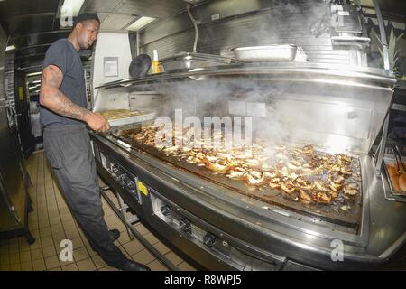 Océan Atlantique (11 mars 2017) - 3e classe spécialiste culinaire Derrick Munford cuisiniers poulet sur le grill pour les marins au cours d'après-midi chow dans l'office d'un navire d'assaut amphibie USS Iwo Jima (DG 7). Iwo Jima est en cours participant à une série de qualifications et certifications dans le cadre de la phase de la formation de base en préparation pour de futures opérations, et les mutations. Banque D'Images