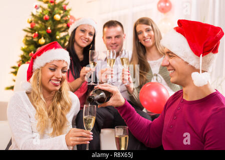 Happy friends célébrer Noël ou Nouvel An avec verre de champagne dans votre intérieur. Banque D'Images