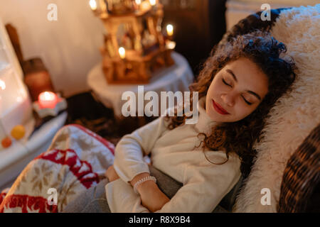 Belle jeune femme aux cheveux bouclés prend un pan avec les lumières de Noël dans l'arrière-plan Banque D'Images