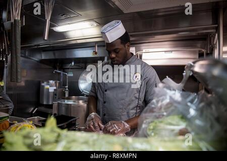 U.S. 5ÈME ZONE DES OPÉRATIONS DE LA FLOTTE (Mar. 11, 2017) -Spécialiste Culinaire 3 classe Brandon Baxley coupe charcuterie pour le sandwich bar à bord du destroyer lance-missiles USS Laboon (DDG 58). Laboon est déployée dans la zone 5e flotte américaine des opérations à l'appui d'opérations de sécurité maritime visant à rassurer les alliés et les partenaires et de préserver la liberté de navigation et la libre circulation du commerce dans la région. Banque D'Images