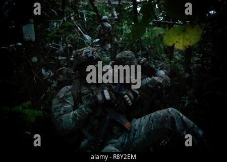 Recon membres de l'équipe de la Royal Australian Air Force n°1 de l'Escadron des Forces de sécurité, U.S. Air Force 824e Escadron de défense de la Base et 736e équipe recon FS attendre la tombée de la nuit dans la jungle après un HH-60 de la Marine au cours de l'effort d'insertion de faire face au nord sur la base aérienne d'Andersen, de Guam, le 27 février, 2017. L'exercice comprend 31 unités et plus de 2 700 militaires de trois pays et poursuit la croissance de strong, interopérables les relations au sein de l'Indo-Asia-région du Pacifique par l'intégration de l'airborne et de commandement et de contrôle. Banque D'Images