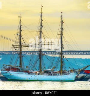 Coucher de scène avec navire à voiles dans le port par le pont 25 avril, Lisbonne, Portugal Banque D'Images