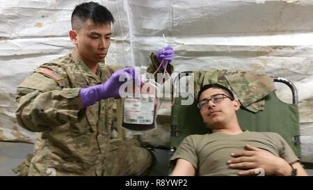 La CPS de l'armée américaine. Gary Tran, personnel médical, C Troop, Escadron de soutien régimentaire, Régiment de cavalerie 2d (à gauche), prépare le Sgt. Eric Lorado concernant la collecte de sang au cours d'une zone de soutien régimentaire exercice défensif dans la zone d'entraînement Grafenwoehr Feb 28, 2017. Soldats ont mené la collecte de sang de la formation afin de valider les procédures défensives RSA et des dommages à l'intérieur 2CR LSF en préparation pour la prochaine sortie 17 Sabre. Banque D'Images