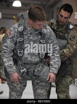 Le sergent parachutiste de l'armée américaine. Austin, la 982e Compagnie de la Caméra de combat, aider autre soldat mettant sur un parachute en préparation d'une opération aéroportée standard à Dobbins Air Force, Marietta, Géorgie, le 3 mars 2017. Parachutistes doit sauter une fois tous les trois mois, pour maintenir leur statut de saut. Banque D'Images