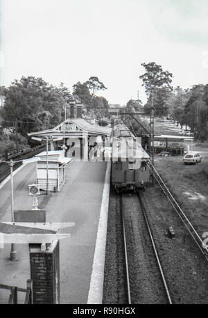 Sydney, Australie, le 13 mars 1977 : un seul decker rouge 'Rattler' ou en acier tire en train Sputnik Turramurra gare sur la rive nord de Sydney. Au premier plan sur la plate-forme est un ensemble de paiement à l'utilisation d'une balance et d'un petit kiosque de bois où des journaux, des cigarettes et chewing-gums Wrigleys a été vendu en semaine. Crédit photo Stephen Dwyer (17 ans) Banque D'Images