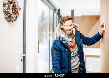L'homme dans des vêtements d'hiver froid réglage de la température avec thermostat électronique à la maison Banque D'Images