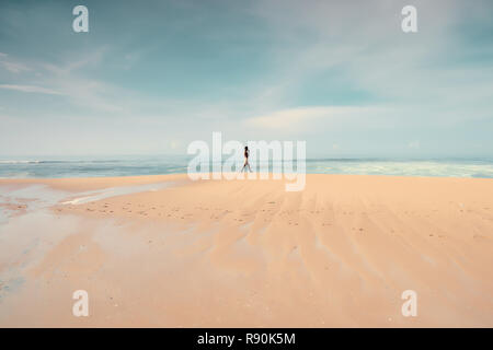 Un homme seul marche sur la plage. Silhouette d'un homme à la plage par la rive. Munnar, Kerala, Inde du Sud. Banque D'Images