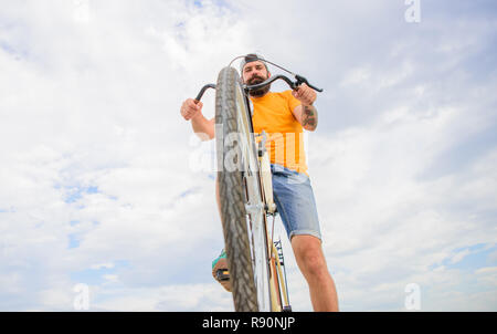 Optimiser le rendement du vélo. Hipster barbu homme manèges location fond voir le fond de ciel. Surmonter les obstacles en vélo. Hipster prêt à effectuer l'affaire. La bicyclette moderne de la culture. Banque D'Images