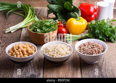 Sélection de légumes frais et de céréales cuites, de céréales et de légumineuses, de plantes en bonne santé l'alimentation végétalienne. Les pois chiches, le quinoa et le sarrasin dans des bols sur rusti Banque D'Images