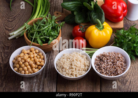 Sélection de légumes frais et de céréales cuites, de céréales et de légumineuses, de plantes en bonne santé l'alimentation végétalienne. Les pois chiches, le quinoa et le sarrasin dans des bols sur rusti Banque D'Images