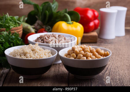 Sélection de légumes frais et de céréales cuites, de céréales et de légumineuses, de plantes en bonne santé l'alimentation végétalienne. Les pois chiches, le quinoa et le sarrasin dans des bols sur rusti Banque D'Images