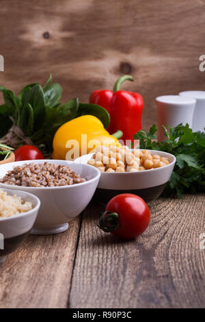 Sélection de légumes frais et de céréales cuites, de céréales et de légumineuses, de plantes en bonne santé l'alimentation végétalienne. Les pois chiches, le quinoa et le sarrasin dans des bols sur rusti Banque D'Images