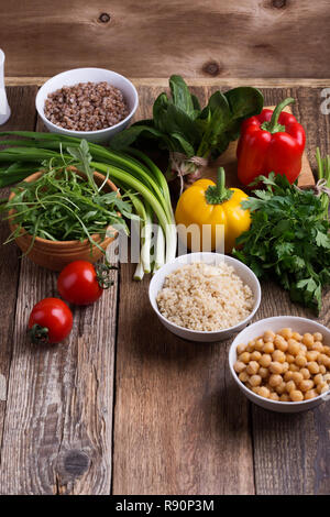 Sélection de légumes frais et de céréales cuites, de céréales et de légumineuses, de plantes en bonne santé l'alimentation végétalienne. Les pois chiches, le quinoa et le sarrasin dans des bols sur rusti Banque D'Images