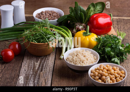 Sélection de légumes frais et de céréales cuites, de céréales et de légumineuses, de plantes en bonne santé l'alimentation végétalienne. Les pois chiches, le quinoa et le sarrasin dans des bols sur rusti Banque D'Images