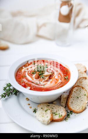 Soupe de tomate sur fond blanc avec la crème et les herbes. Vue de dessus, copy space Banque D'Images