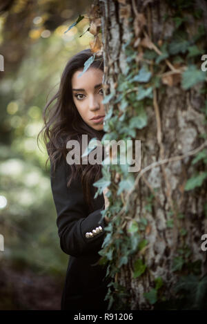 Belle femme de se cacher derrière un arbre Banque D'Images