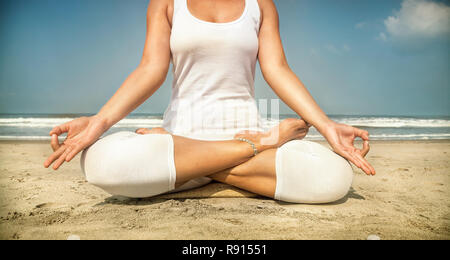 Woman doing yoga méditation en costume blanc sur la plage à Goa, Inde Banque D'Images