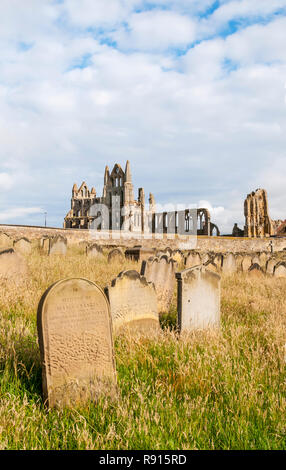 Les ruines de l'abbaye de Whitby vu à travers les pierres tombales dans le cimetière de l'église St Mary. Banque D'Images