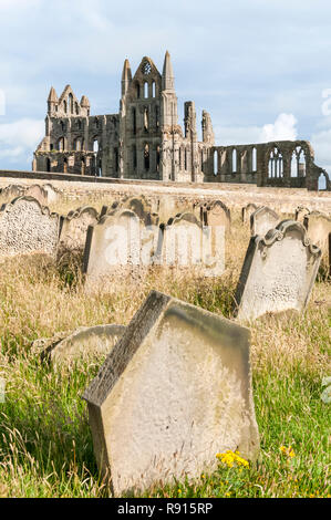 Les ruines de l'abbaye de Whitby vu à travers les pierres tombales dans le cimetière de l'église St Mary. Banque D'Images