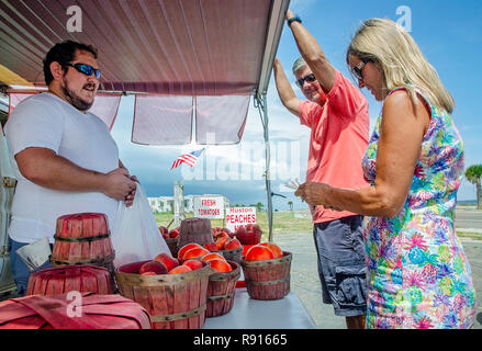 Stand de fruits Paul propriétaire parle Verzwyvelt avec les clients comme ils achètent Ruston pêches, 12 juin 2018, à Pass Christian, Mississippi. Banque D'Images