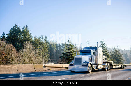 Bonnet puissant l'idole américain noir et blanc gros camion camion semi long-courrier avec semi-remorque vide l'étape vers le bas sur le déplacement de l'autoroute large avec barrière de sécurité Banque D'Images