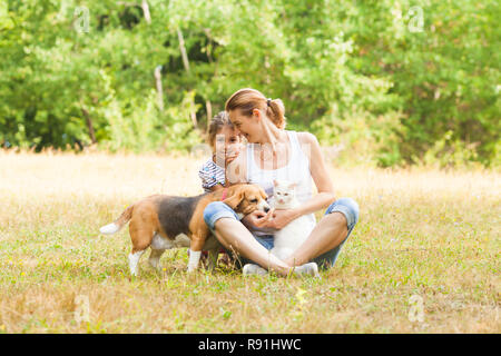 Couple adorable fille et Maman assise sur une herbe avec leurs animaux de compagnie Banque D'Images