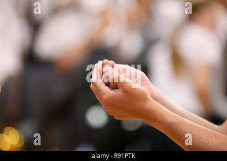 Close up image d'un paroissiens les mains jointes recevant le pain au cours de la sainte communion d'un prêtre catholique à la messe. Banque D'Images